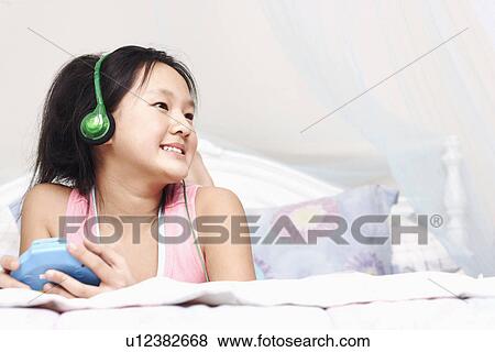 Stock Photo - Low angle view of a girl listening to music on an MP3 player. Fotosearch