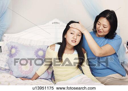 Stock Photography - Mother's hand on her daughter's forehead. Fotosearch