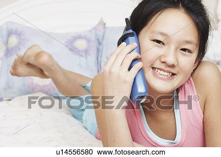 Stock Image - Portrait of a girl using a cordless telephone. Fotosearch