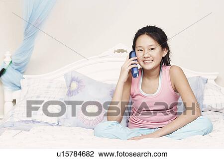 Stock Image - Portrait of a girl using a cordless telephone. Fotosearch
