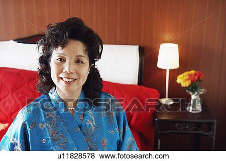 Portrait of a mature woman sitting on the bed smiling View Large Photo Image Stock Photo - Portrait of a mature woman sitting on the bed smiling. Fotosearch