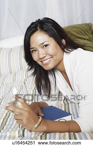Stock Image - Portrait of a young woman holding a wineglass smiling. Fotosearch