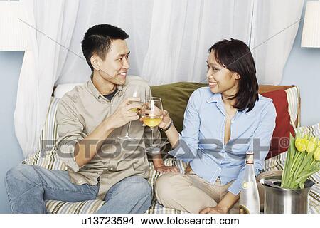 Young couple sitting on the bed toasting with wineglasses View Large Photo Image Picture - Young couple sitting on the bed toasting with wineglasses. Fotosearch