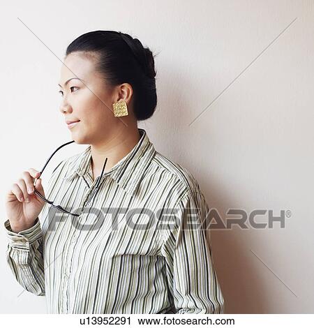 Close-up of a businesswoman holding eyeglasses and looking away View Large Photo Image Stock Image - Close-up of a businesswoman holding eyeglasses and looking away. Fotosearch