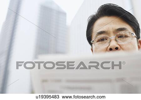 Stock Image - Close-up of a mature man reading a newspaper. Fotosearch