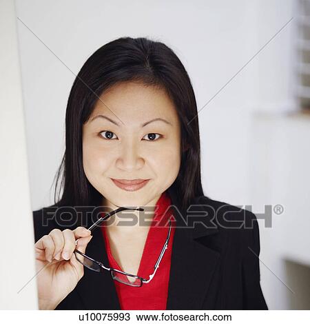 Stock Image - Portrait of a businesswoman holding a newspaper and smiling. Fotosearch