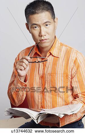 Portrait of a mid adult man holding eyeglasses and a newspaper View Large Photo Image Stock Image - Portrait of a mid adult man holding eyeglasses and a newspaper. Fotosearch