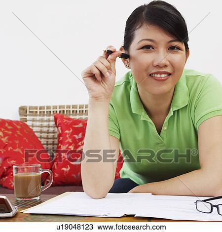 Stock Image - Portrait of a young woman leaning against a table and smiling. Fotosearch