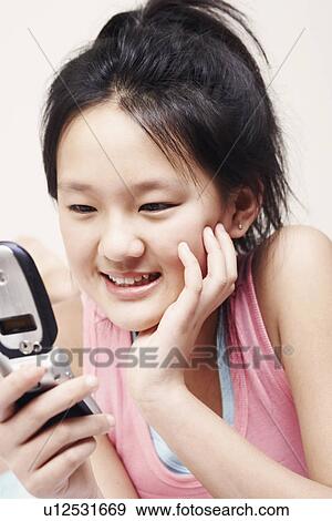 Close-up of a girl holding a mobile phone View Large Photo Image Stock Photo - Close-up of a girl holding a mobile phone. Fotosearch