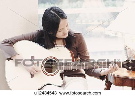 Stock Image - Close-up of a girl playing the guitar. Fotosearch