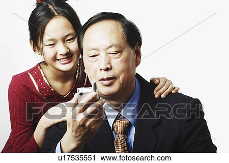 Stock Image - Close-up of granddaughter standing behind her grandfather. Fotosearch