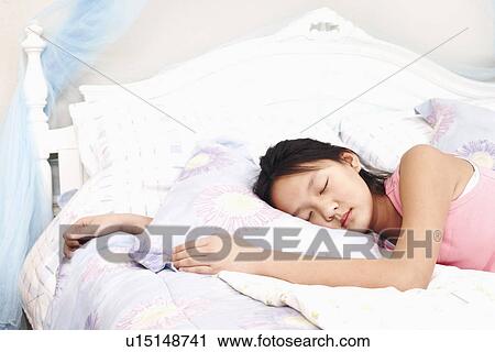 Stock Image - Girl lying on the bed with her eyes closed. Fotosearch
