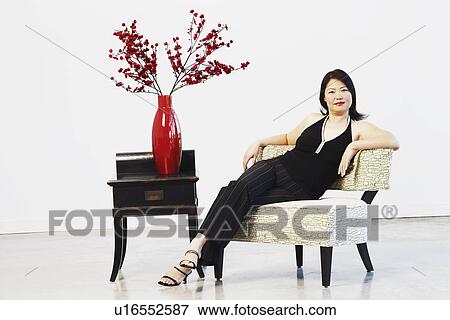 Portrait of a mid adult woman sitting on a chair View Large Photo Image Stock Photo - Portrait of a mid adult woman sitting on a chair. Fotosearch