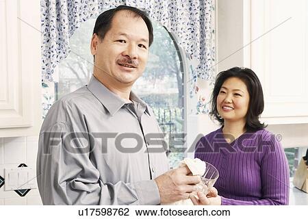 Portrait of a senior man cleaning a glass with a mature woman standing behind him View Large Photo Image Stock Image - Portrait of a senior man cleaning a glass with a mature woman standing behind him. Fotosearch
