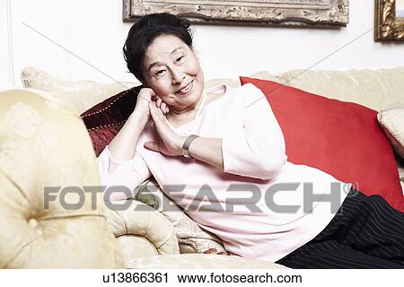 Stock Image - Portrait of a senior woman sitting on a couch. Fotosearch