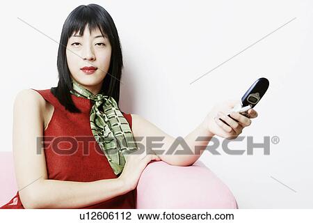 Portrait of a young woman holding a mobile phone View Large Photo Image Stock Image - Portrait of a young woman holding a mobile phone. Fotosearch