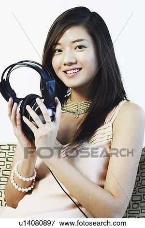 Stock Photo - Portrait of a young woman holding headphones. Fotosearch