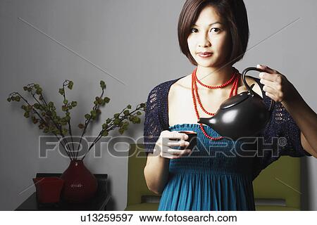 Portrait of a young woman pouring tea into a tea cup View Large Photo Image Stock Photo - Portrait of a young woman pouring tea into a tea cup. Fotosearch