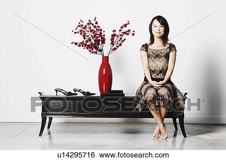 Stock Photograph - Portrait of a young woman sitting on a table. Fotosearch