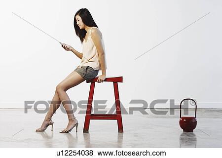 Side profile of a young woman holding a mobile phone View Large Photo Image Stock Photo - Side profile of a young woman holding a mobile phone. Fotosearch