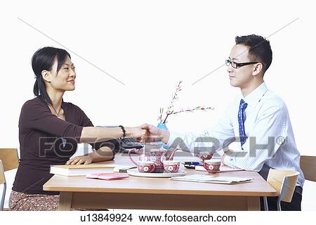 Businessman and a businesswoman sitting on chairs shaking hands View Large Photo Image Picture - Businessman and a businesswoman sitting on chairs shaking hands. Fotosearch