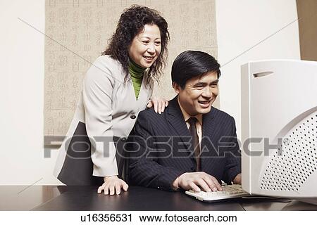 Stock Image - Businesswoman and a businessman using a computer. Fotosearch