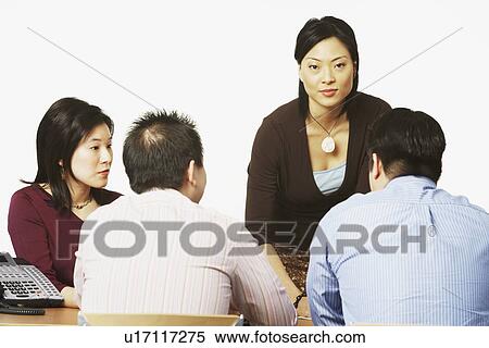 Stock Photography - Businesswoman talking to her colleagues in a conference room. Fotosearch