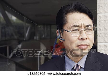 Stock Photography - Close-up of a businessman wearing a hands free device thinking. Fotosearch