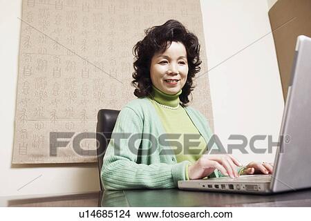 Picture - Close-up of a businesswoman using a laptop smiling. Fotosearch
