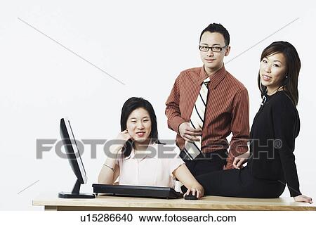 Stock Image - Portrait of a businessman and two businesswomen smiling. Fotosearch