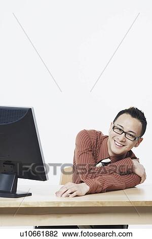 Stock Image - Portrait of a businessman sitting in front of a flat screen monitor. Fotosearch