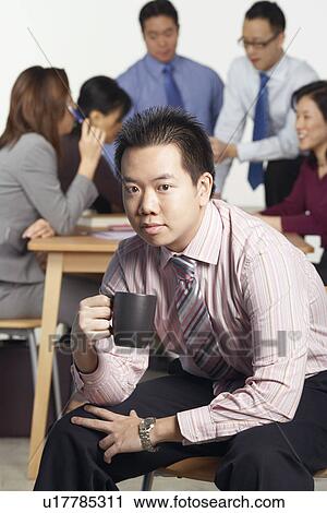 Portrait of a businessman sitting on a chair holding a coffee cup View Large Photo Image Stock Image - Portrait of a businessman sitting on a chair holding a coffee cup. Fotosearch