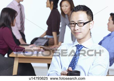 Stock Photography - Portrait of a businessman sitting on a chair holding a coffee cup. Fotosearch