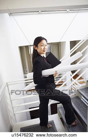 Portrait of a businesswoman carrying rolled up charts and smiling View Large Photo Image Stock Image - Portrait of a businesswoman carrying rolled up charts and smiling. Fotosearch