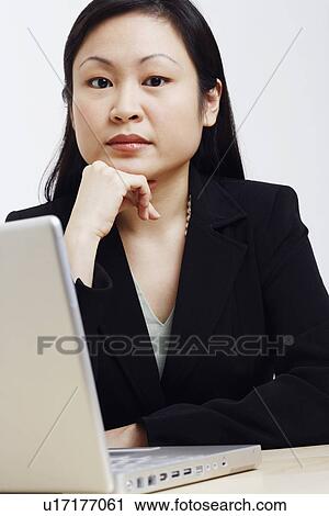 Stock Image - Portrait of a businesswoman sitting in front of a laptop. Fotosearch