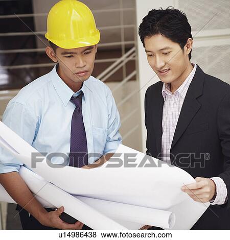 Stock Photo - Side profile of a businessman and an architect looking at blueprints. Fotosearch