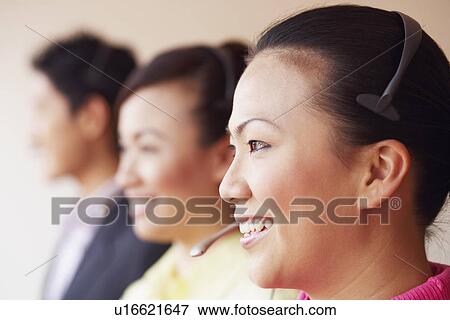 Side profile of a female customer service representative smiling with two colleagues View Large Photo Image Stock Photo - Side profile of a female customer service representative smiling with two colleagues. Fotosearch