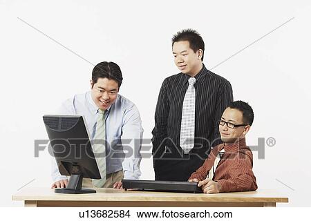 Picture - Three businessmen looking at a computer monitor. Fotosearch