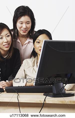 Three businesswomen looking at a computer View Large Photo Image Stock Photo - Three businesswomen looking at a computer. Fotosearch