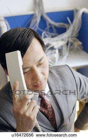 Close-up of a businessman holding a telephone receiver in a server room View Large Photo Image Stock Photograph - Close-up of a businessman holding a telephone receiver in a server room. Fotosearch