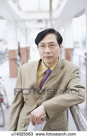 Stock Image - Portrait of a businessman leaning against a railing. Fotosearch
