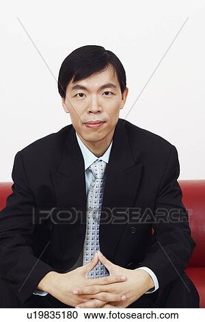 Portrait of a businessman sitting on a couch with his hands clasped View Large Photo Image Stock Image - Portrait of a businessman sitting on a couch with his hands clasped. Fotosearch