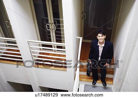 Stock Photo - Portrait of a businessman standing on a staircase and smiling. Fotosearch