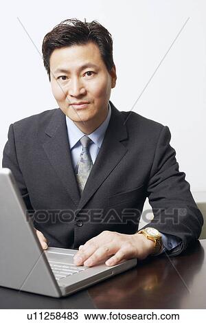 Stock Image - Portrait of a businessman using a laptop. Fotosearch