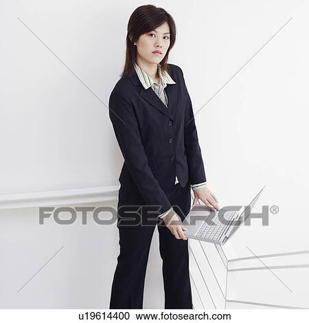 Stock Image - Portrait of a businesswoman holding a laptop and posing. Fotosearch