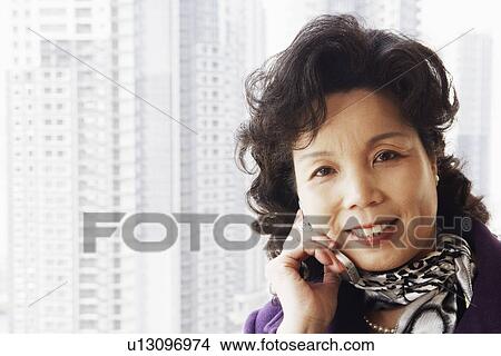 Picture - Portrait of a businesswoman talking on a mobile phone smiling. Fotosearch