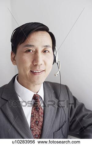 Stock Photograph - Portrait of a customer service representative wearing a headset smiling. Fotosearch