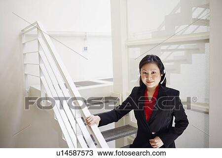 Stock Image - Portrait of a female customer service representative wearing a headset and smiling. Fotosearch