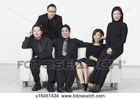 Picture - Three young men and two young women on a couch. Fotosearch