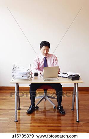 Stock Photo - Businessman using a laptop in an office. Fotosearch